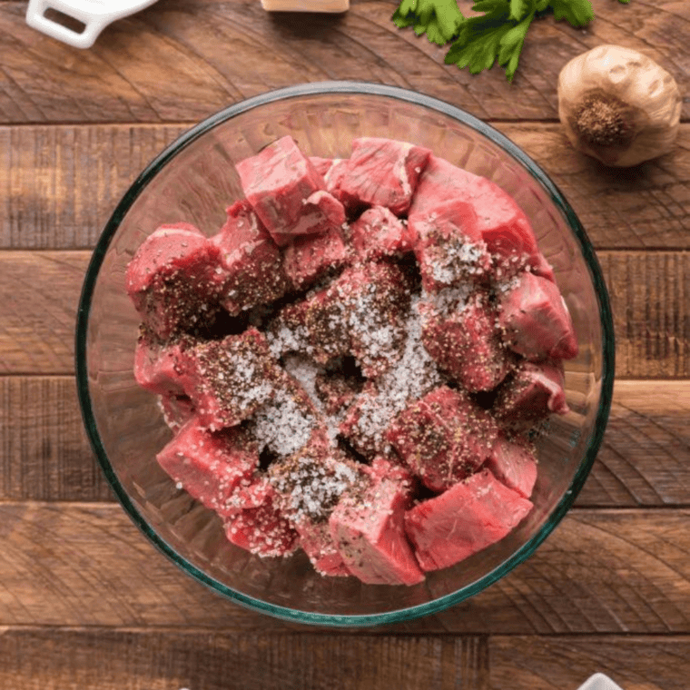 Cut steak in a mixing bowl, with herbs and spices.