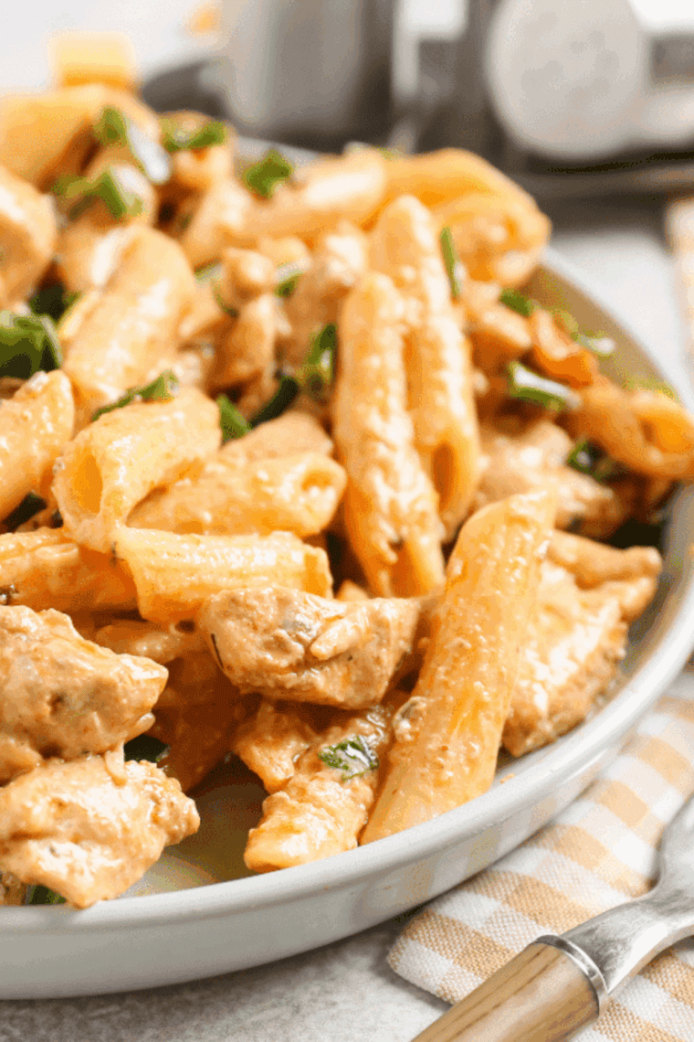 Seasoned diced chicken breast cooking in an air fryer basket for a healthy Cajun pasta recipe.