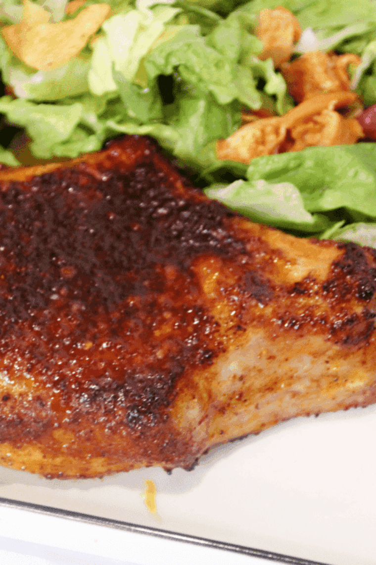 Juicy Air Fryer Chile Lime Pork Chop garnished with lime wedges and fresh herbs.
