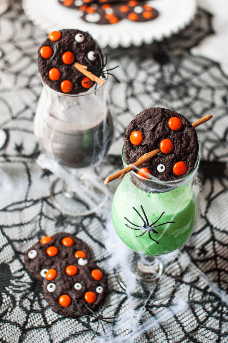 Thick, dark chocolate Halloween cookies loaded with vibrant orange and green sprinkles and white chocolate chips, showing a soft and chewy interior.