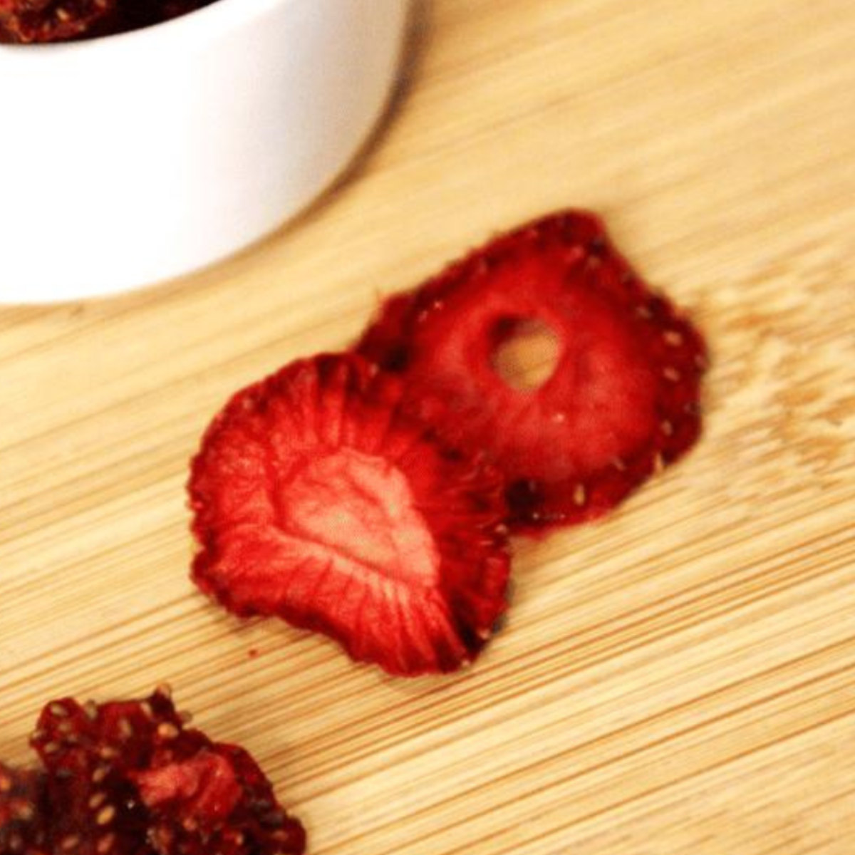 Dipping crispy dehydrated strawberries into yogurt, showing a delicious way to enjoy the snack.