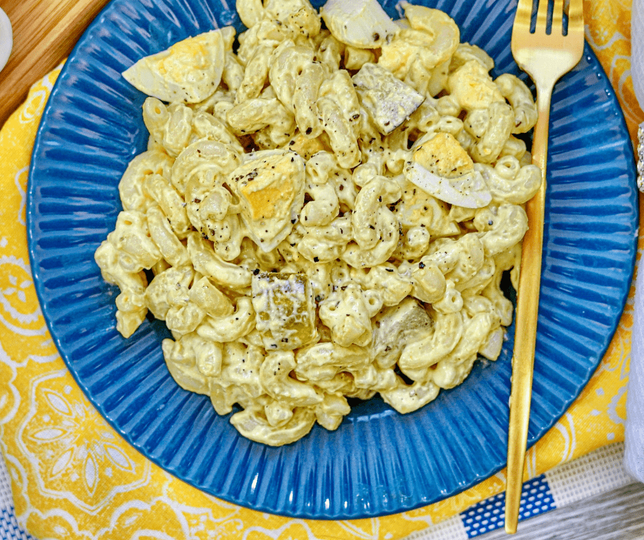 Creamy deviled egg pasta salad in bowl with macaroni, chopped eggs, pickles, and mustard dressing mixed together rich side dish.