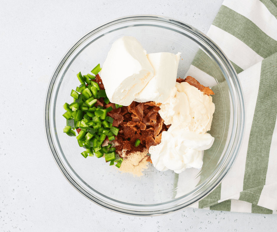 Cream cheese added to the bowl with chopped jalapeños.