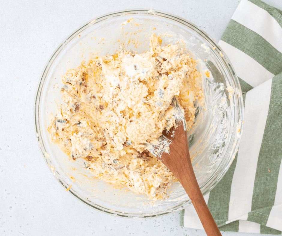Shredded cheese being mixed into the jalapeño and cream cheese mixture.