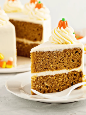 Frosted air fryer pumpkin layer cake on a white plate with cinnamon dusted on top