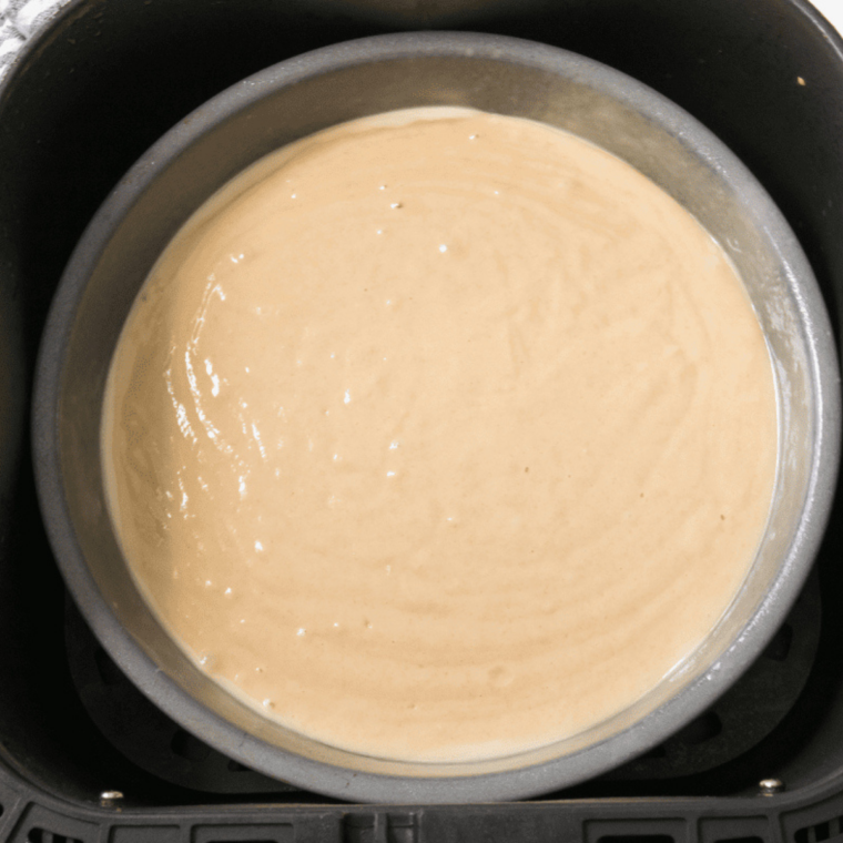 Pumpkin cake batter divided into two greased air fryer cake pans
