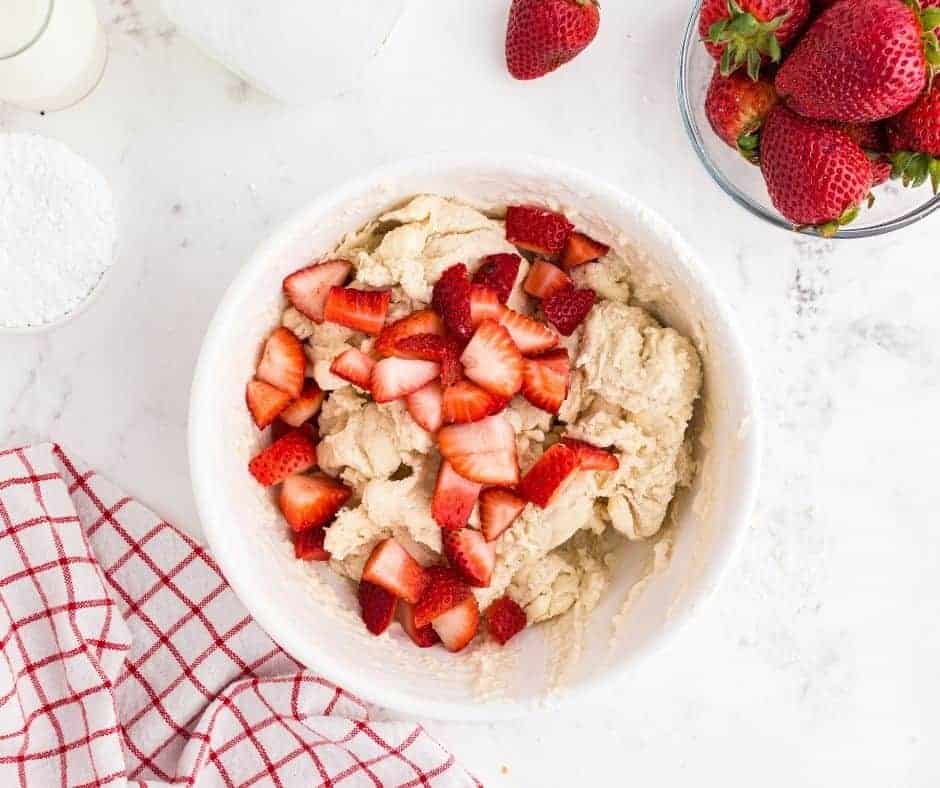 Folding fresh strawberries into muffin batter and air frying muffins until golden and cooked through