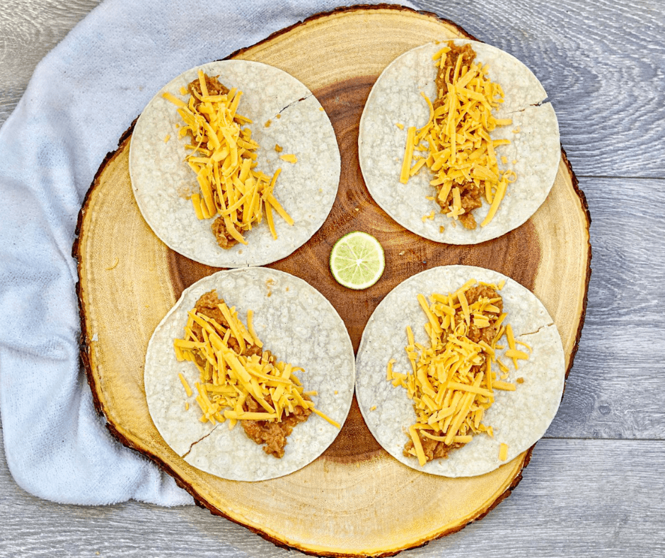 Corn tortilla rolled tightly around the bean and cheese filling, seam-side down