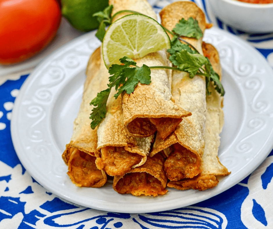 A plate of crispy bean and cheese air fryer taquitos served with salsa and guacamole