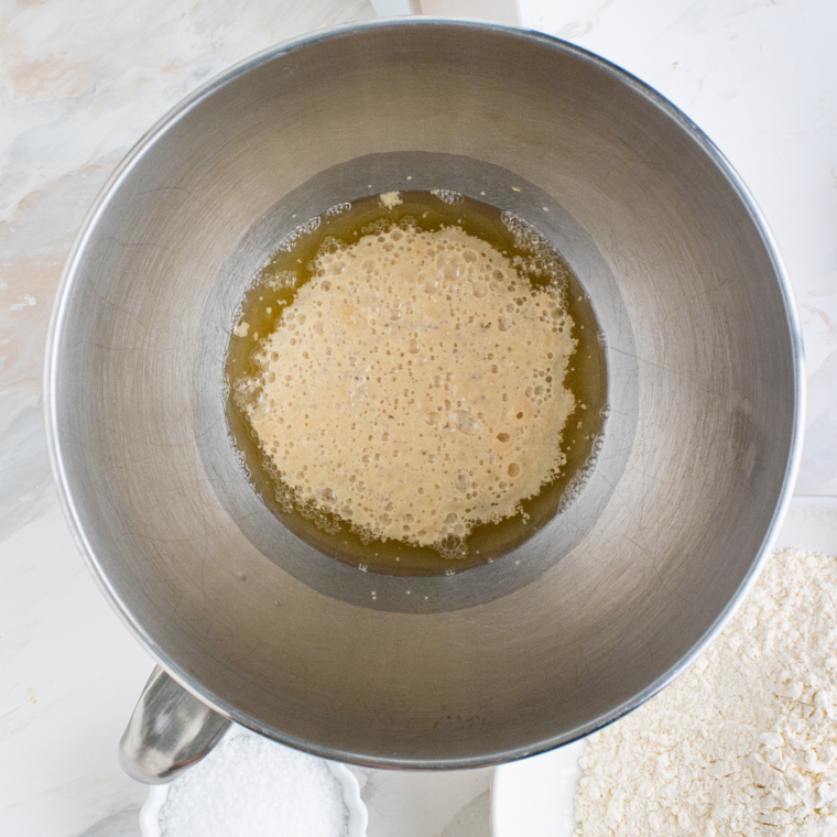 Yeast and sugar dissolving in warm water in a bowl until foamy