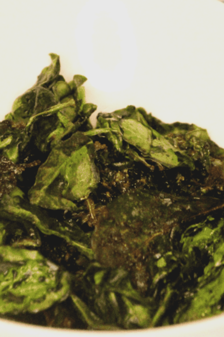 Golden, crispy spinach chips fresh from the air fryer, served in a bowl.