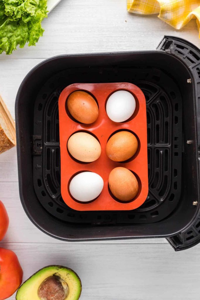 Air fryer eggs placed in a trivet inside basket set at 250°F for 16 minutes for even cooking and easy hard-boiled results.