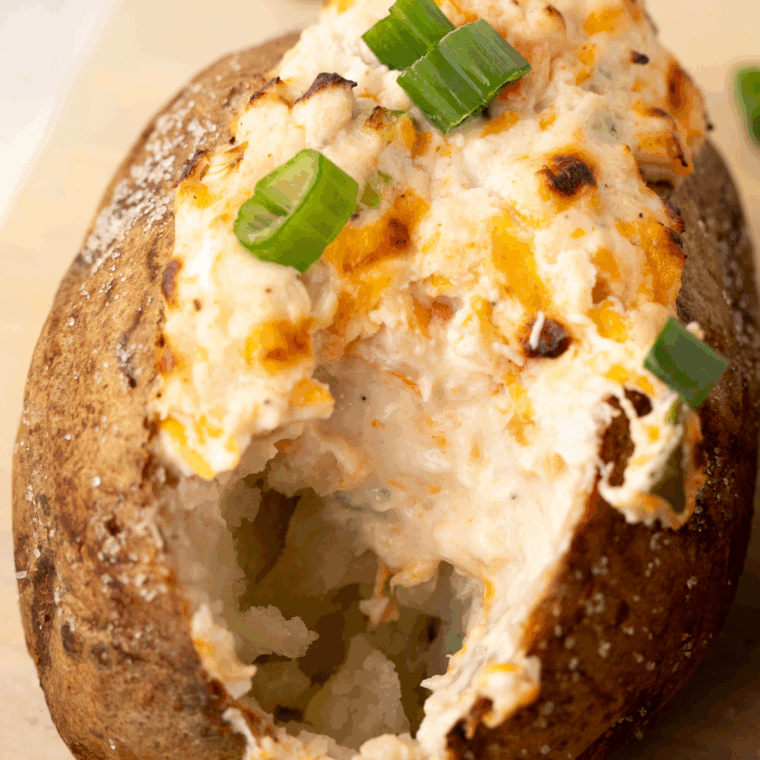 Golden baked potato with crispy skin, topped with butter and fresh herbs