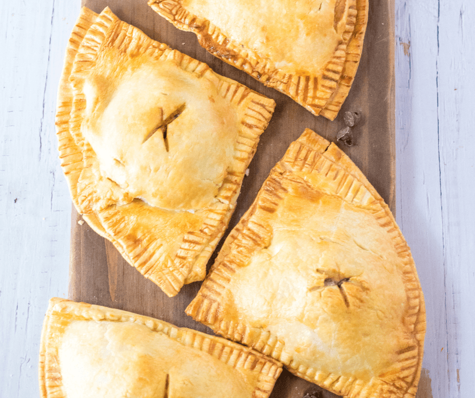 Air Fryer S'mores Hand Pies served with a side of chocolate dipping sauce and fresh berries on a rustic wooden table.