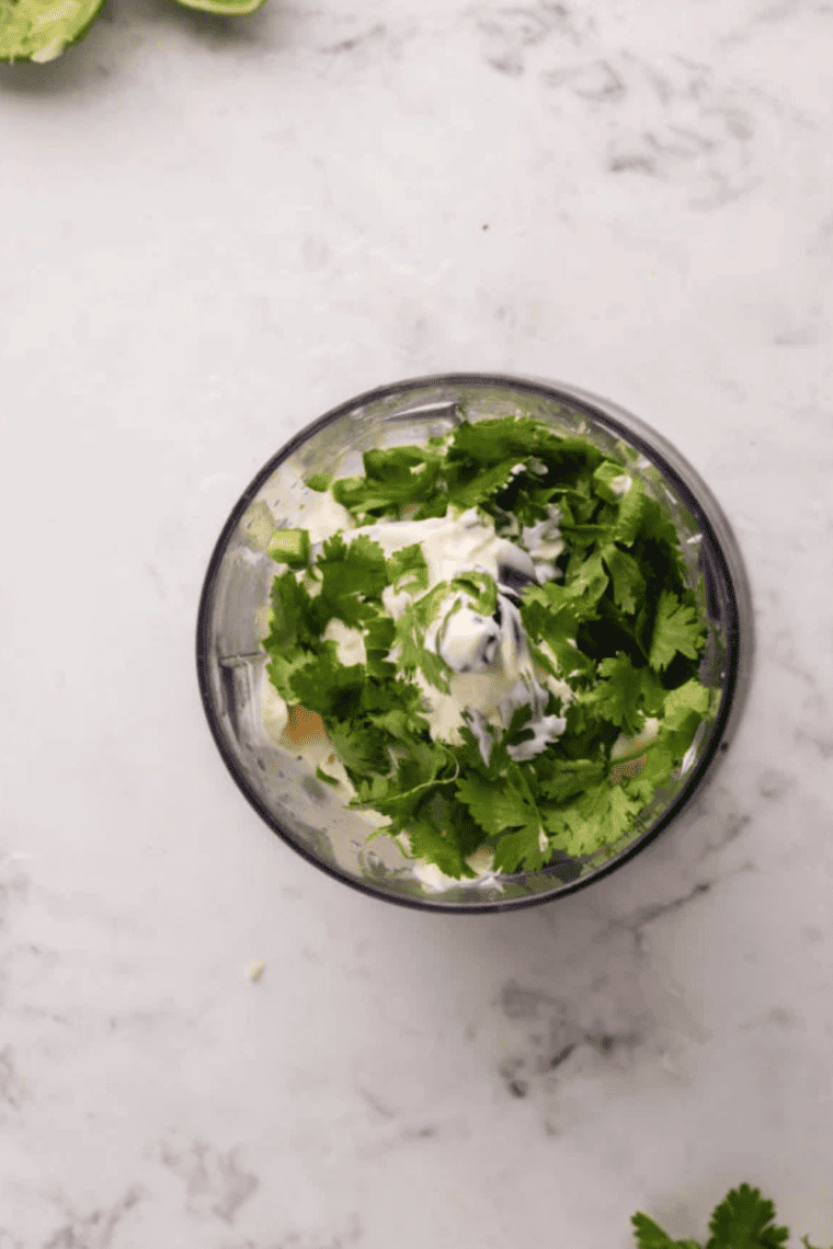 Combining Greek yogurt, olive oil, apple cider vinegar, lemon juice, and sea salt in a bowl and stirring until smooth.