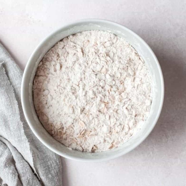 Whisking flour, rolled oats, and cinnamon together in a mixing bowl