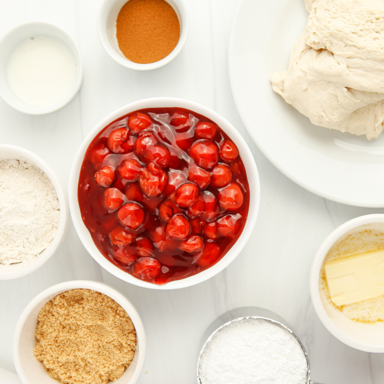 Ingredients for air fryer cherry dessert pizza: pizza dough, cherry pie filling, butter, brown sugar, flour, and cinnamon