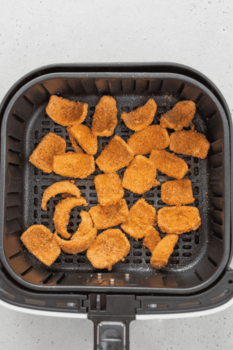 Frozen onion petals arranged in a single layer inside an air fryer basket before cooking