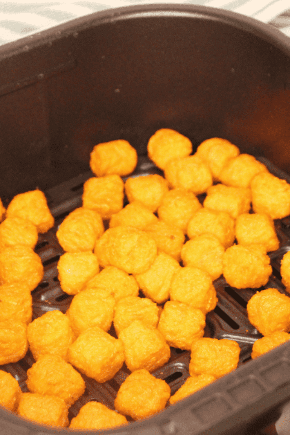 Air Fryer Frozen Sweet Potato Tots in air fryer basket.
