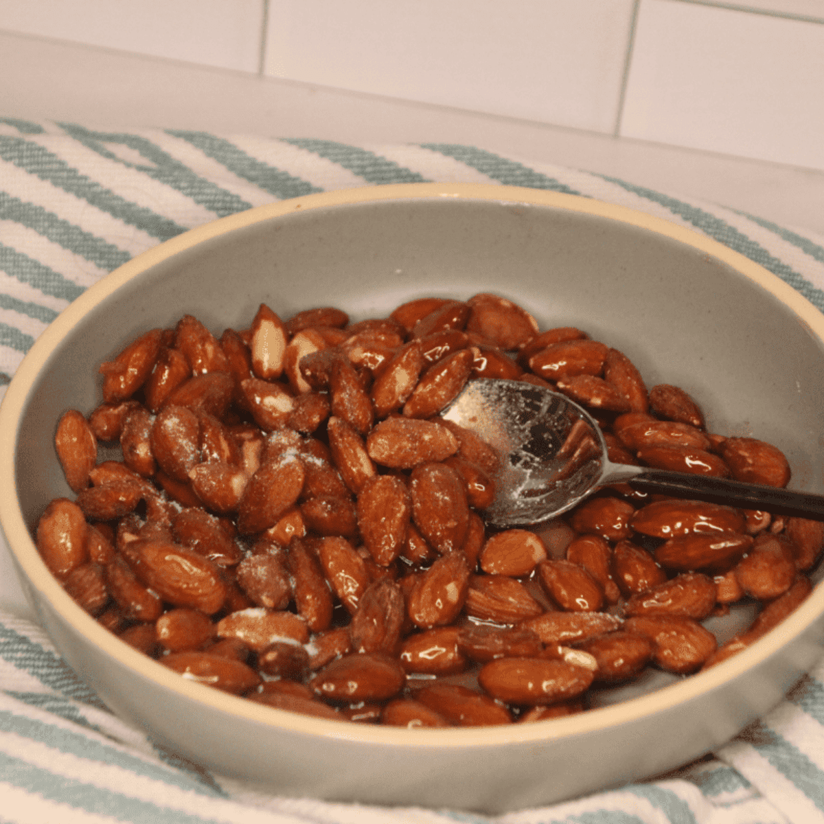 Mixing raw almonds with honey, sugar, salt, and black pepper in a small bowl until evenly coated.