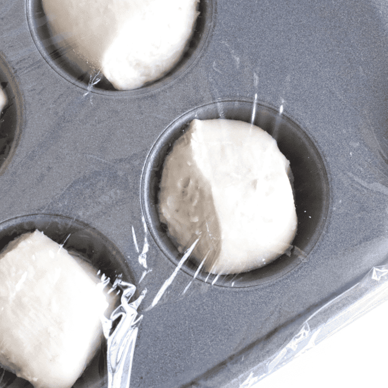 Step one of making Air Fryer Sloppy Joe Bites: Thawing and cutting rolls in half before placing them in a mini muffin tin sprayed with cooking spray.