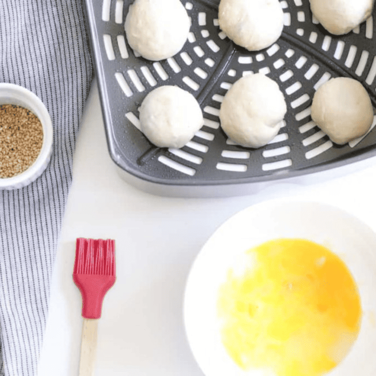 Placing filled rolls in the air fryer basket, pinched side down, with space in between for Air Fryer Sloppy Joe Bites.