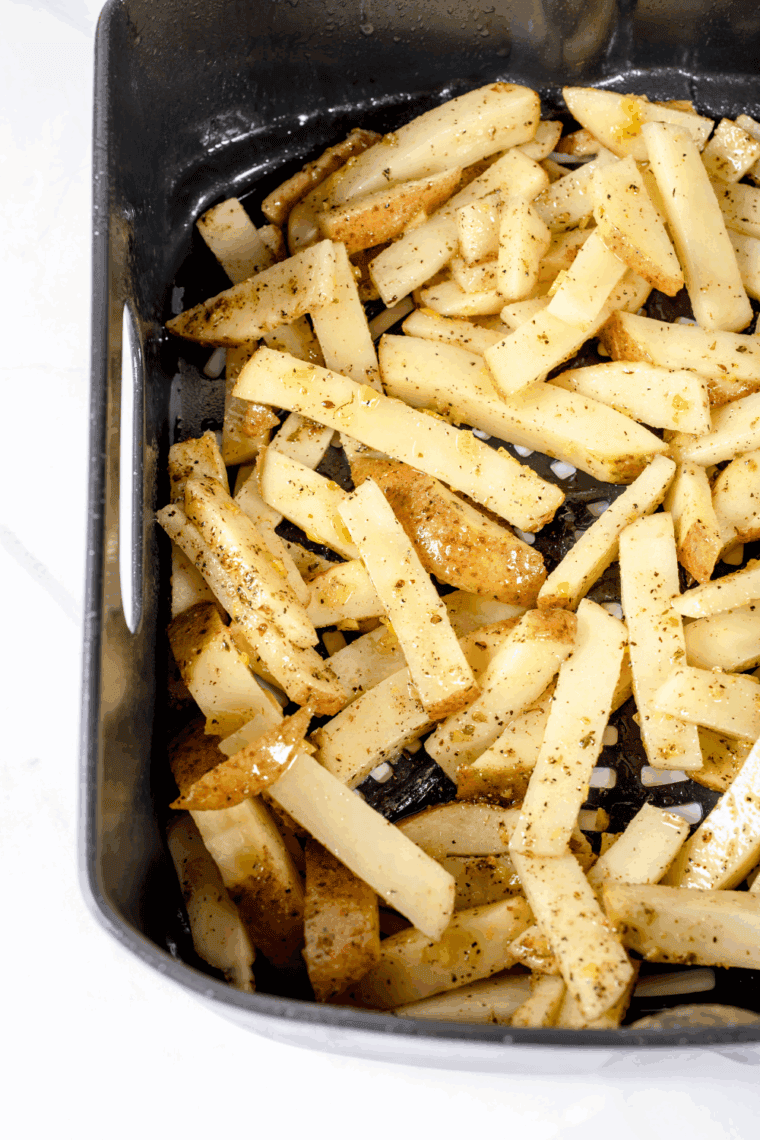 Cut potatoes arranged in a single layer in an air fryer basket, cooking for 15–20 minutes until golden and crispy, shaken halfway through.