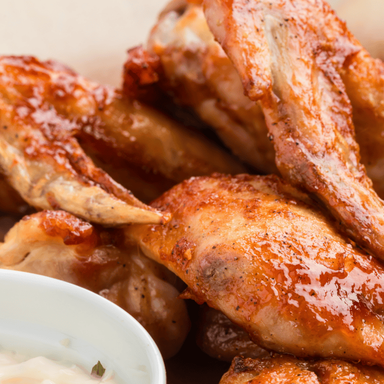 Plate of crispy Wingstop-style mild chicken wings coated in buttery sauce, served hot with dipping sauce.