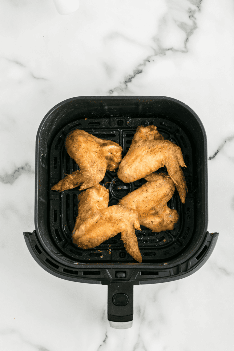 Tossing crispy wings in mild buttery sauce until coated