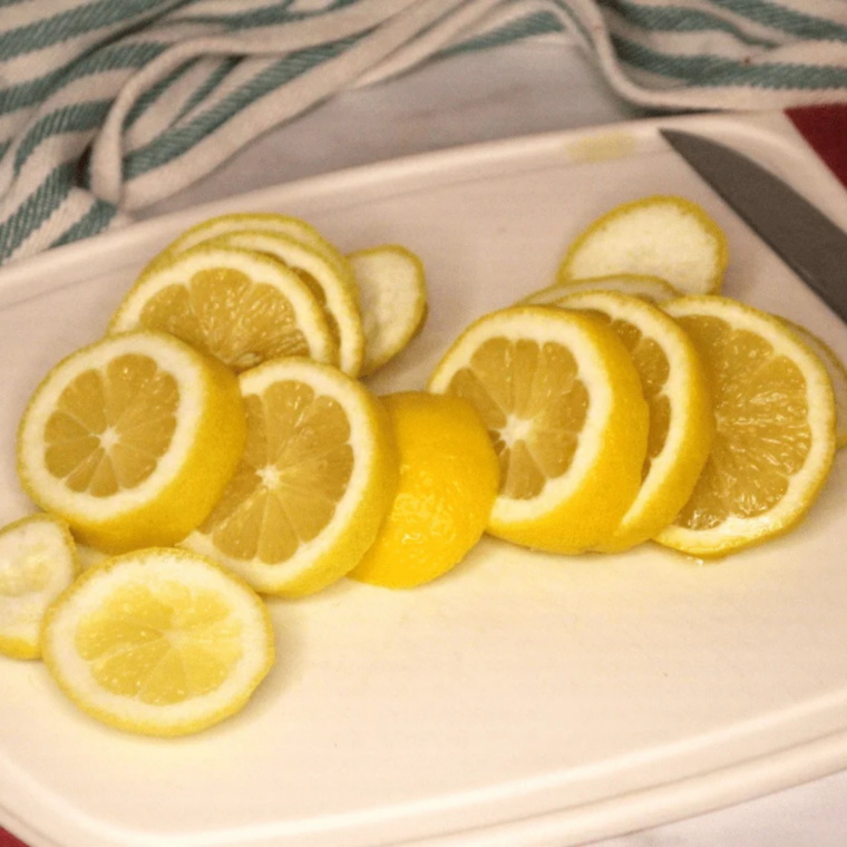 Sliced lemons cut into even thin rounds on a cutting board, showing uniform thickness for air fryer