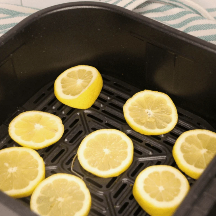 Raw lemon slices arranged in a single layer inside an air fryer basket, spaced evenly for proper airflow.