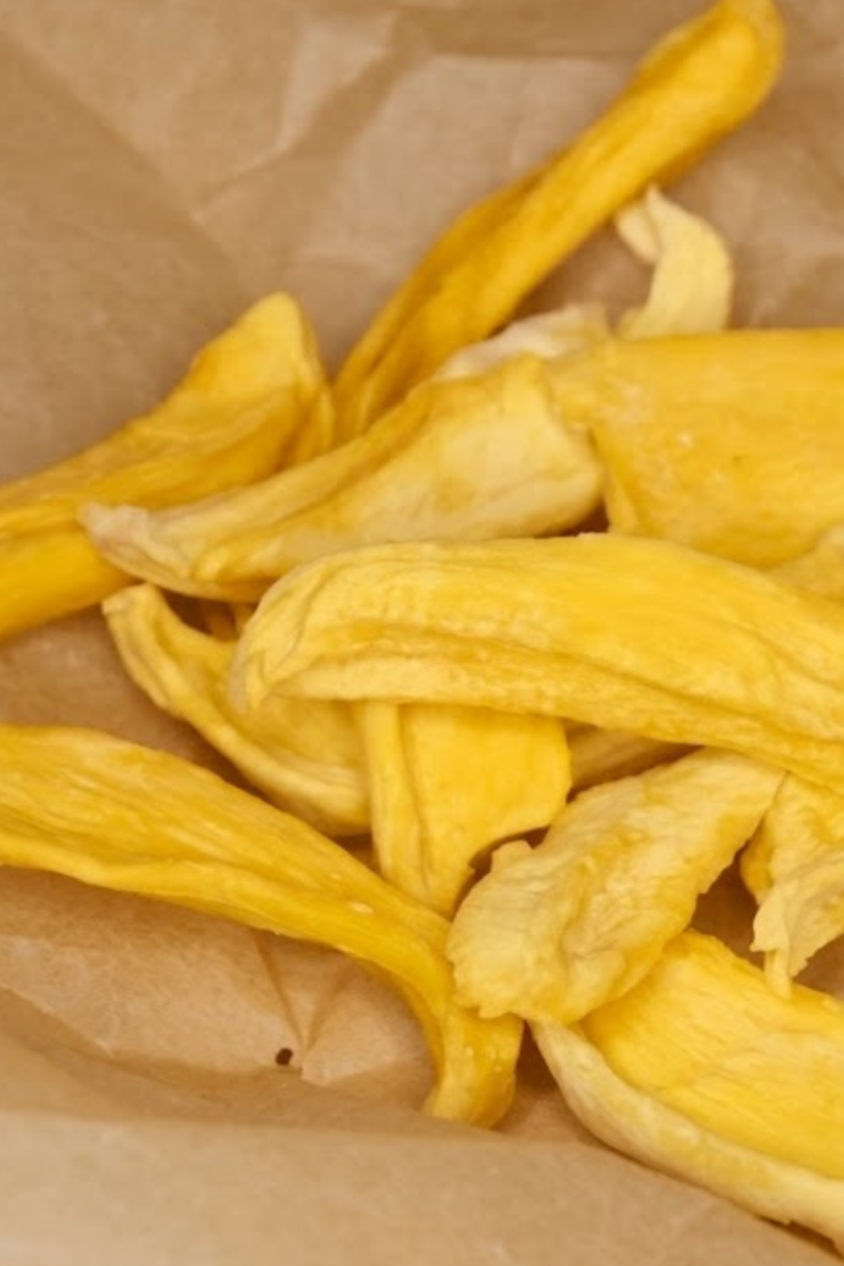 Golden mango slices dehydrating in an air fryer, turning into a healthy homemade dried fruit snack.