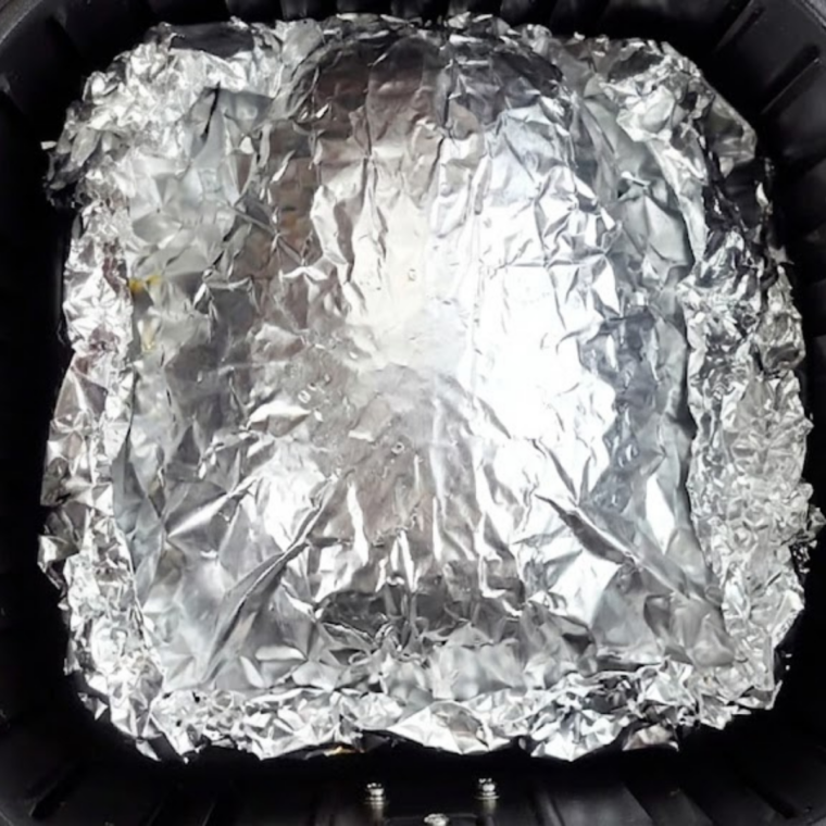 Foil-wrapped brisket placed in air fryer basket cooking at 360°F for slow steam braising.