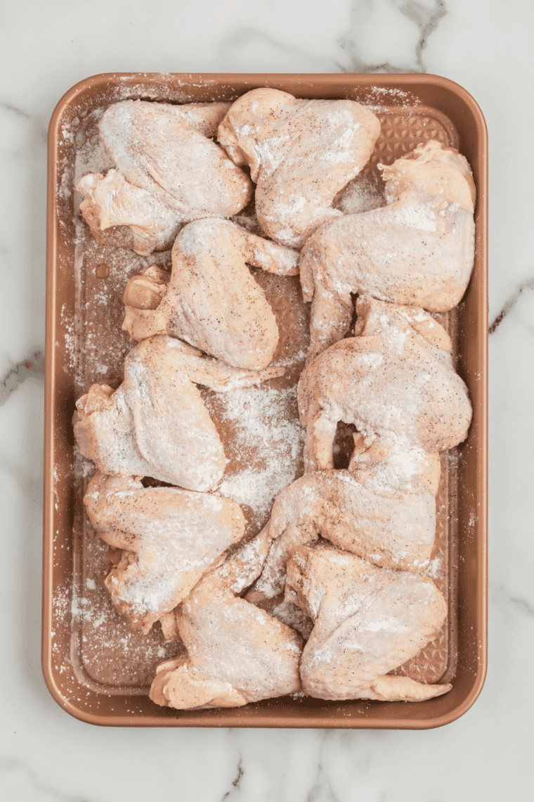 Seasoning chicken wings with salt, pepper, paprika, garlic, and cayenne.