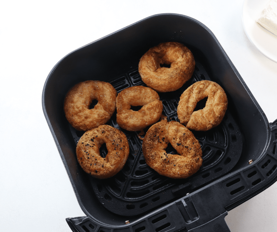 Air fryer basket with frozen bagels, showcasing their initial frozen state