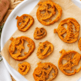 Sweet potato jack-o-lanterns with carved faces on a white platter