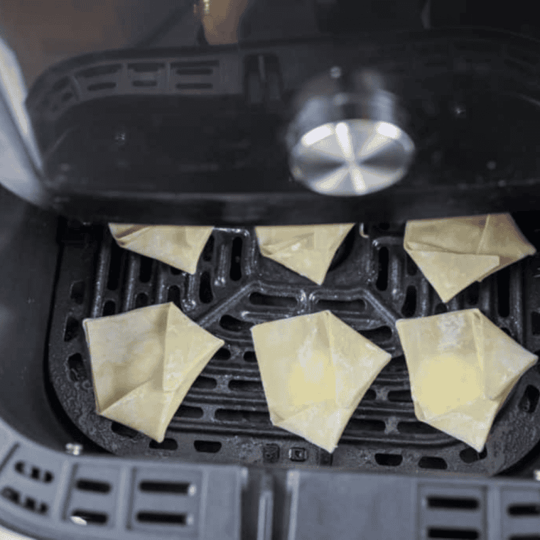 Place the folded cream cheese wontons in a single layer in the air fryer basket, spray with oil, and cook at 375°F for 8-10 minutes until golden brown.
