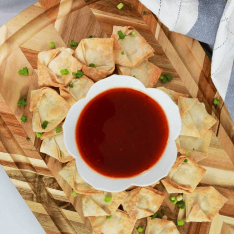 Golden-brown Air Fryer Cream Cheese Rangoons arranged on a plate, filled with a creamy cheese mixture and served with a dipping sauce.