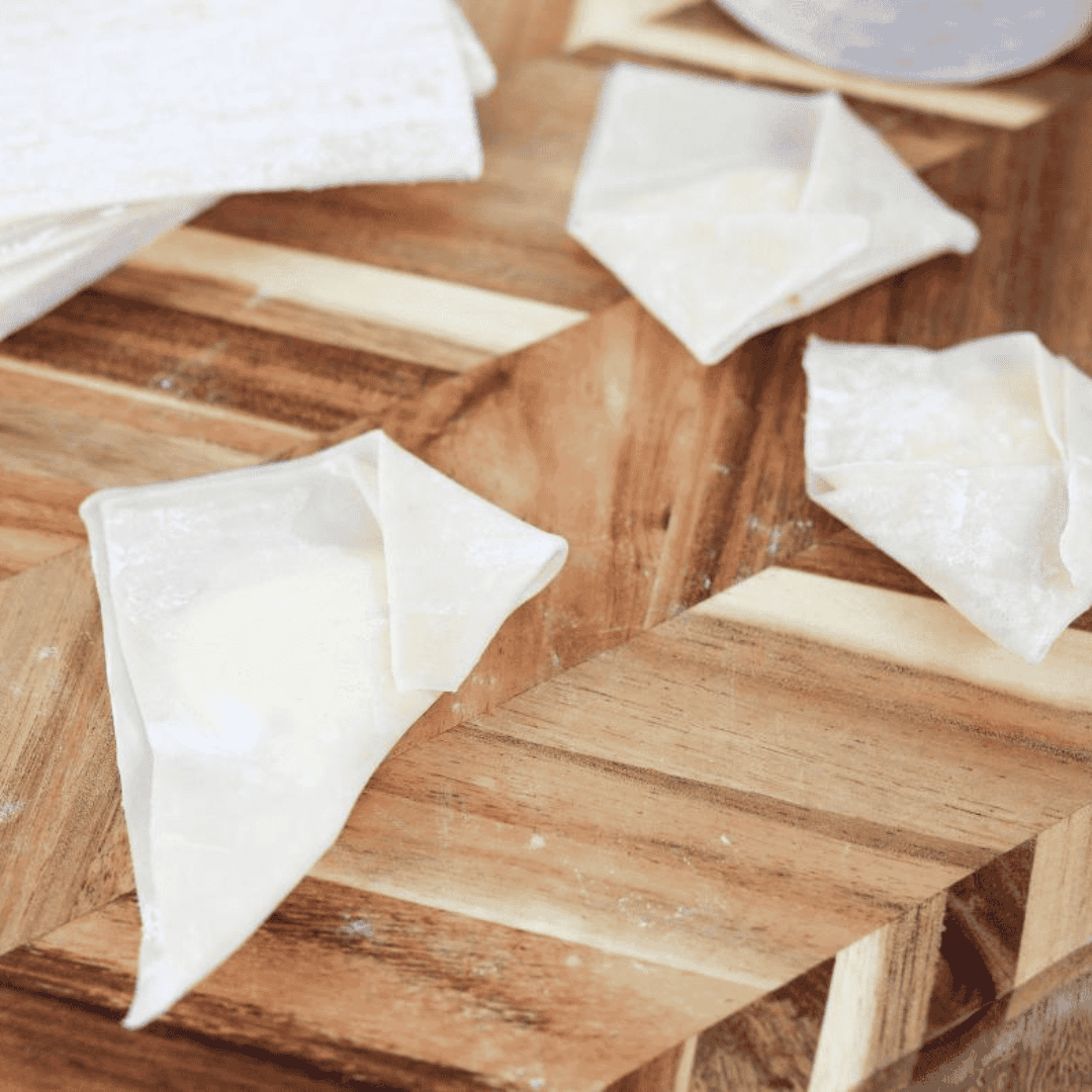 Folding a wonton wrapper into a pocket style, with brushed edges for sealing, to create a perfect cream cheese Rangoon.