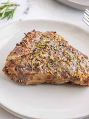Frozen lamb chops in the air fryer, cooked golden-brown and garnished with fresh rosemary