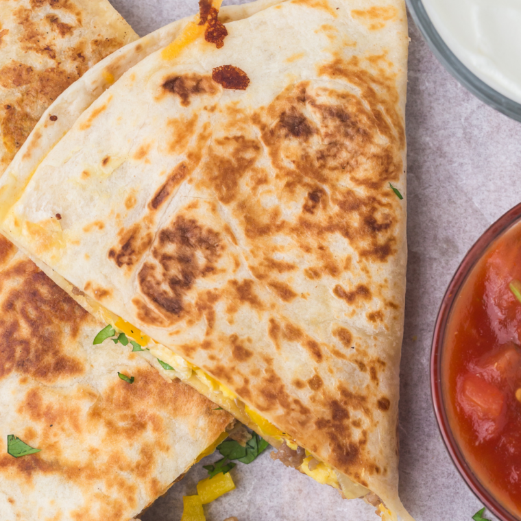 Homemade chicken quesadilla cooking on a Blackstone griddle with melted Mexican cheese