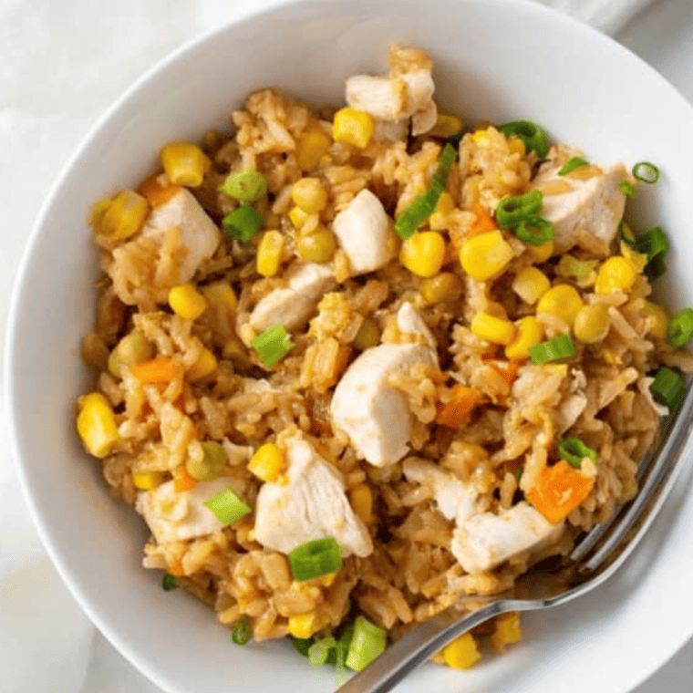 A bowl of homemade Panda Express fried rice with eggs, peas, carrots, and green onions, served in a white dish.