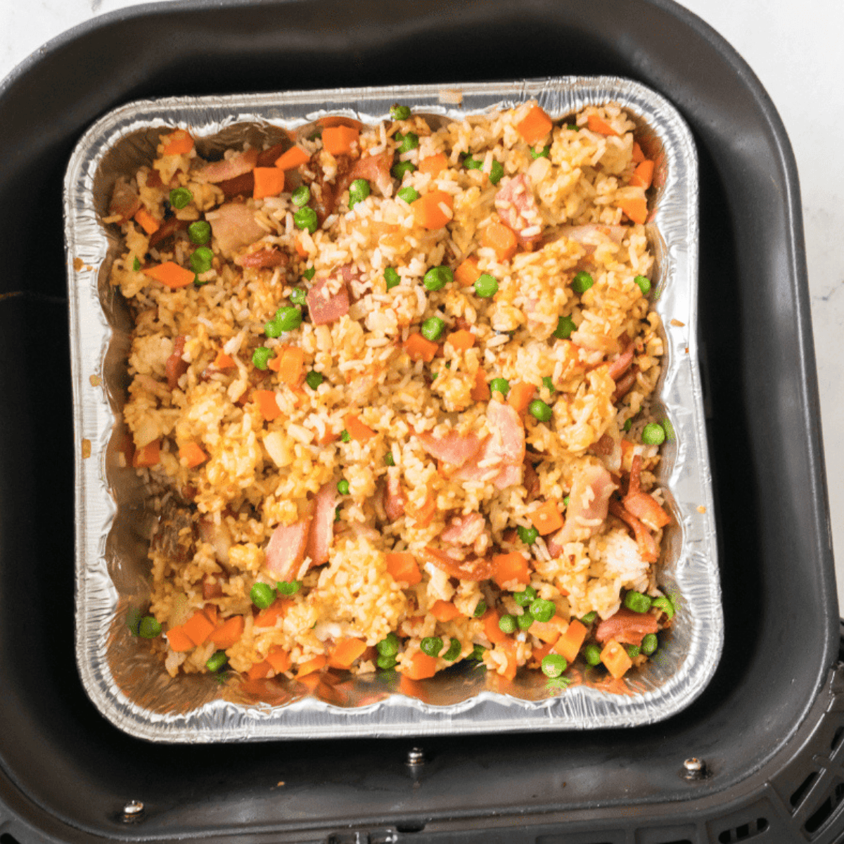 Fried rice in an oven-safe dish placed in an air fryer basket, cooking at 360°F for 15-20 minutes.