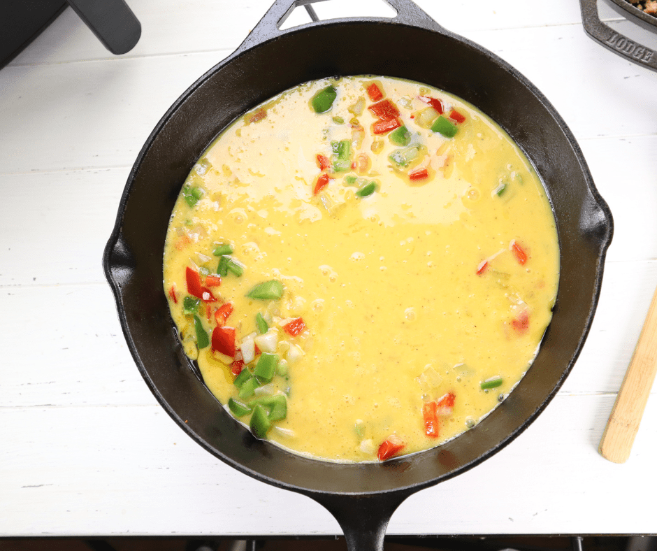 Filling tortillas with scrambled eggs, sausage, and cheese to assemble the breakfast burritos.
