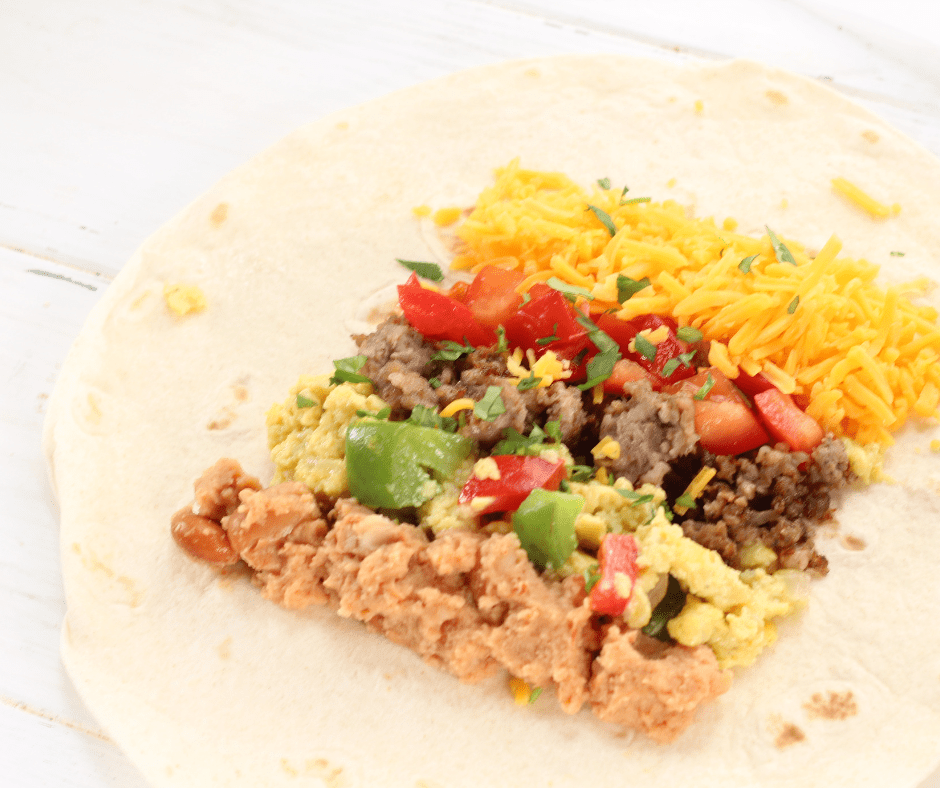 Filling tortillas with scrambled eggs, sausage, and cheese to assemble the breakfast burritos.