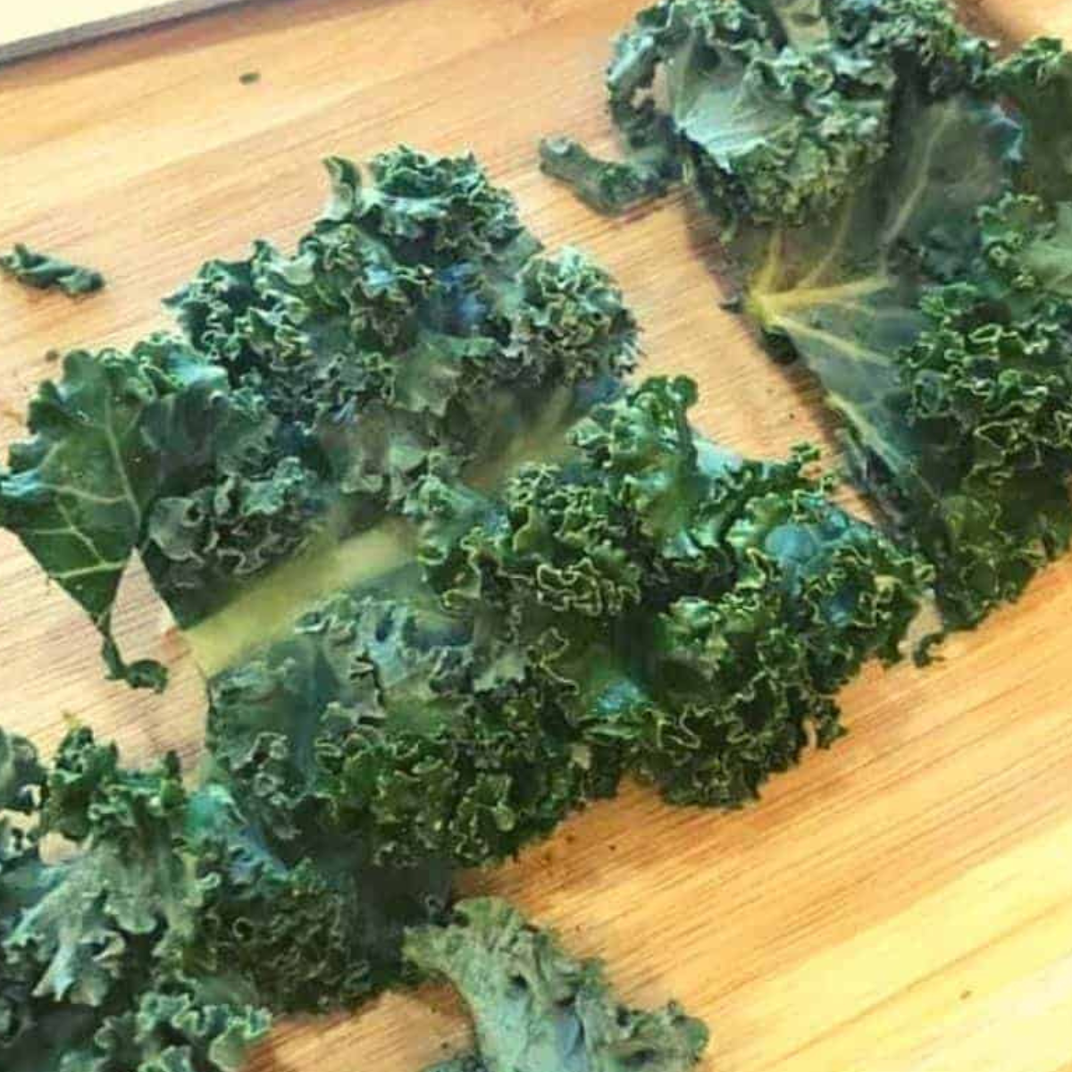 Preparing kale chips on cutting board.