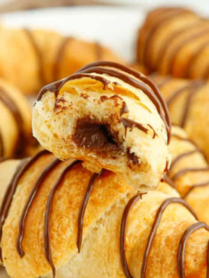 Air fryer peanut butter chocolate crescent rolls stacked on a white plate with chocolate drizzle