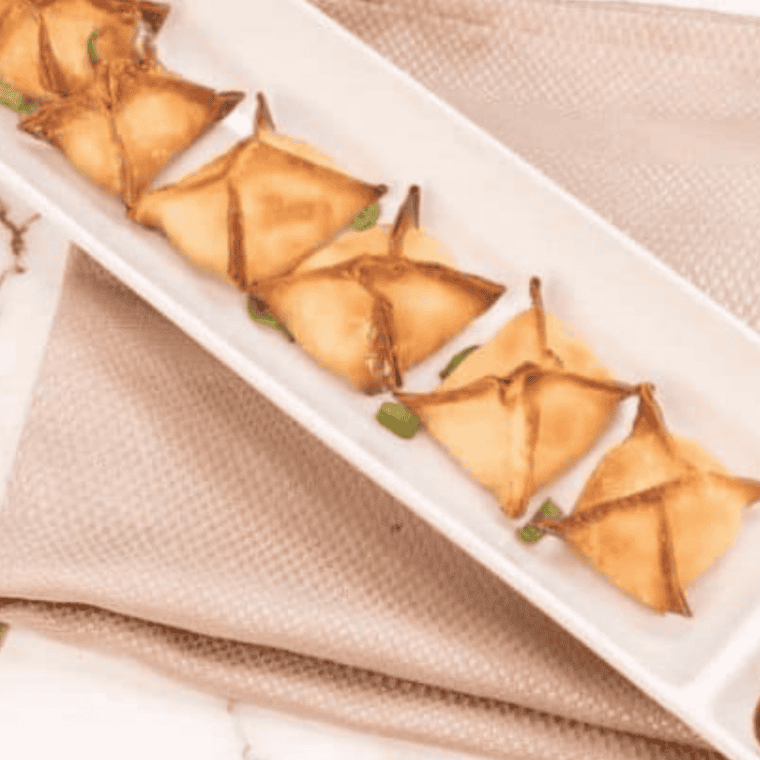 Crab rangoon arranged in an air fryer basket, golden and crispy after reheating, with a crunchy exterior and creamy filling visible at the edges.
