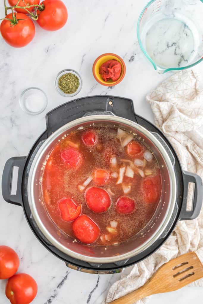 "Adding diced tomatoes and vegetables to the Instant Pot for the Panera creamy tomato soup."