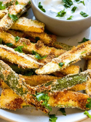 Crispy keto air fryer zucchini fries with golden parmesan coating served with ranch dipping sauce